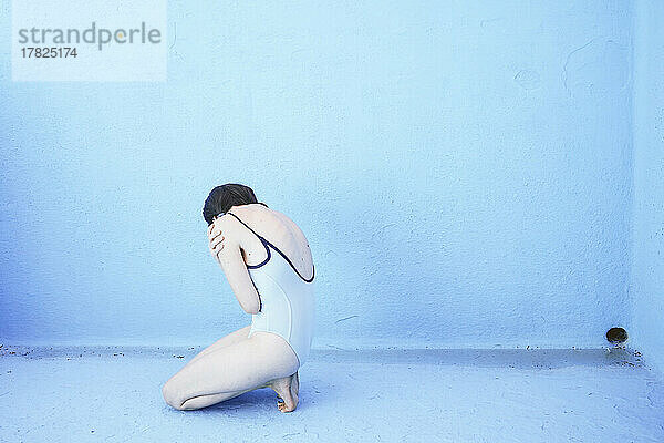 Traurige Frau sitzt vor der blauen Poolwand