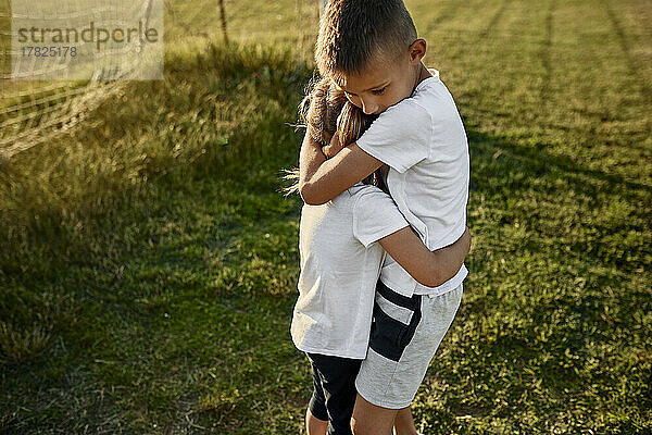 Junge umarmt Schwester auf Sportplatz