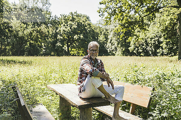 Glücklicher älterer Mann sitzt am Picknicktisch im Park
