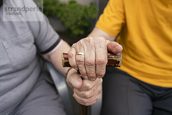 Hände eines älteren Paares mit Gehstock