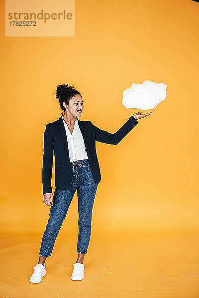 Glückliche Geschäftsfrau mit Wolke vor gelbem Hintergrund