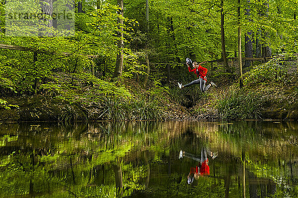 Junge Frau springt über See im Wald