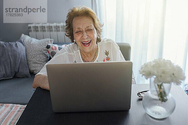 Glückliche ältere Frau  die zu Hause Laptop benutzt