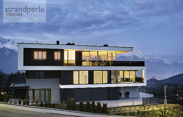 Österreich  Tirol  beleuchtete Fassade eines luxuriösen dreistöckigen Hauses in den Bergen in der Abenddämmerung