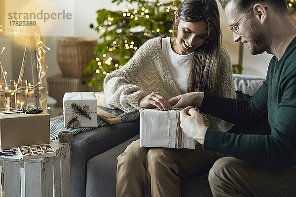 Glückliche Frau und Mann  die zu Hause Weihnachtsgeschenk einpacken