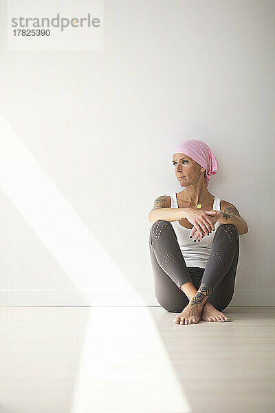 Frau sitzt an einem sonnigen Tag auf dem Boden im Yogastudio