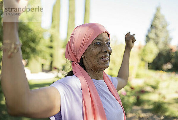 Fröhliche ältere Frau beim Training im Park mit gebeugten Muskeln