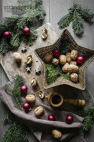 Studio shot of cutting board  star shaped wicker basket  twigs  Christmas ornaments  walnuts and simple nutcracker