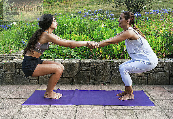 Yoga-Trainer und Teenager-Mädchen trainieren gemeinsam im Park