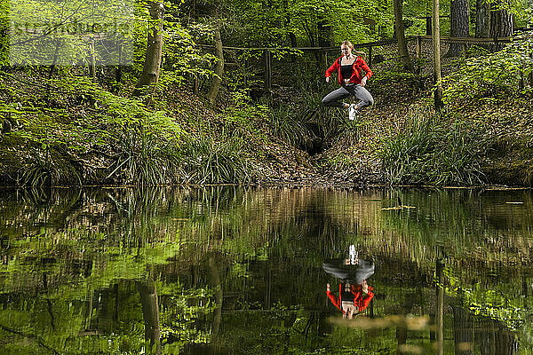 Frau springt über See im Wald