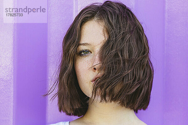 Teenage girl with brown hair in front of purple cargo container
