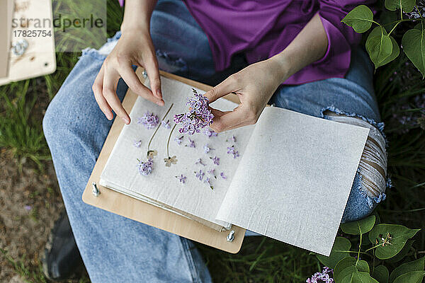 Woman holding lilac flowers sitting with book