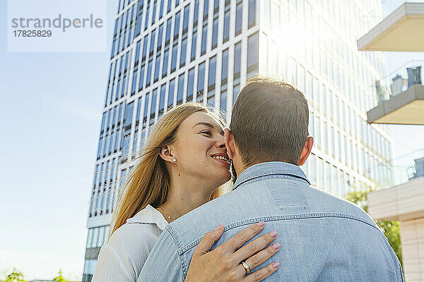 Glückliche Frau umarmt Mann vor Gebäude