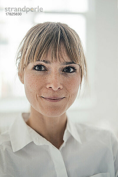 Lächelnde Geschäftsfrau im weißen Hemd im Büro