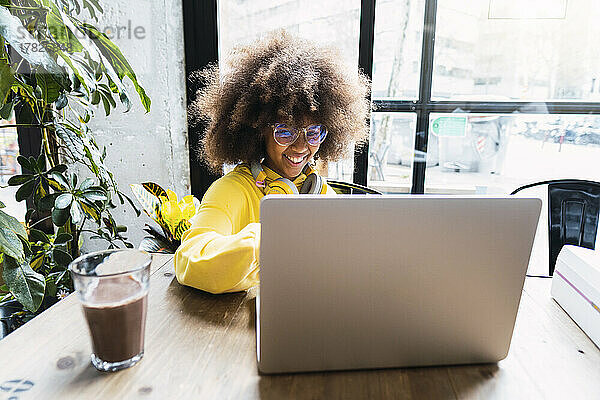 Mädchen benutzt Laptop mit Tee auf dem Tisch im Café