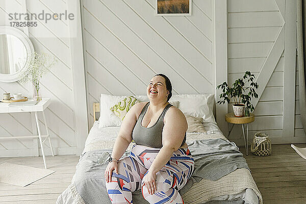 Cheerful woman sitting on bed at home