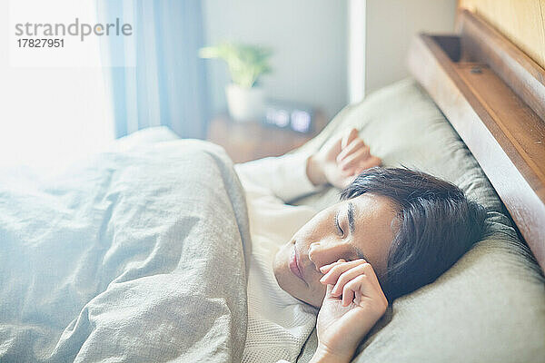 Japanischer Mann morgens im Bett