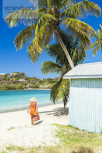 Tourist in orangefarbenem Kleid am palmengesäumten Strand  Antigua  Leeward Islands  Westindien  Karibik  Mittelamerika