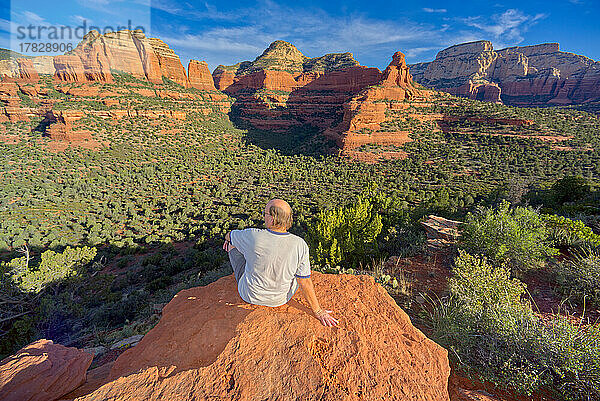 Ein Mann sitzt auf dem Gipfel des Mescal Mountain mit Blick auf den Deadmans Pass in Sedona  Arizona  Vereinigte Staaten von Amerika  Nordamerika