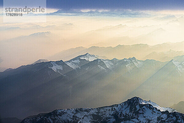 Flug über die schneebedeckten Gipfel der Lepontiner und Tessiner Alpen  beleuchtet von Sonnenstrahlen am romantischen Himmel bei Sonnenuntergang  Schweiz  Europa