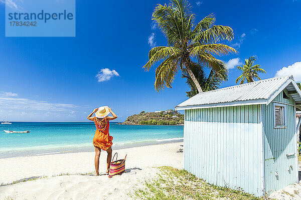 Schöne Frau mit Strohhut und Kleid entspannt am tropischen Strand  Antigua  Leeward Islands  Westindien  Karibik  Mittelamerika