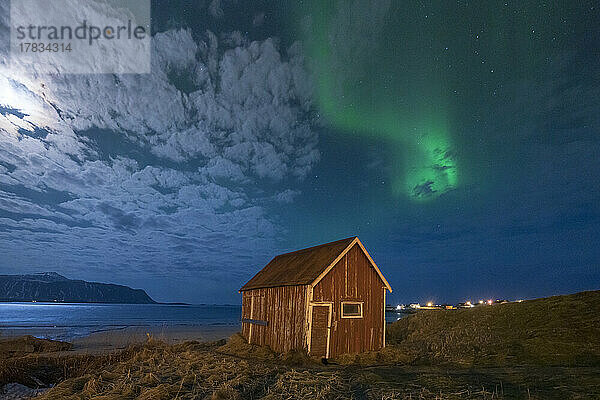 Rote Hütte unter dem hellen Nachthimmel  beleuchtet von Mond und Aurora Borealis (Nordlicht)  Ramberg  Nordland  Lofoten  Norwegen  Skandinavien  Europa