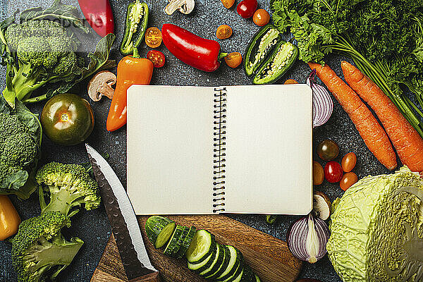 Leerer Notizblock und verschiedenes frisches Gemüse auf rustikalem Betontisch
