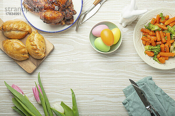 Ostergericht - pastellfarbene Eier  Brathähnchen  Gemüse und Brötchen