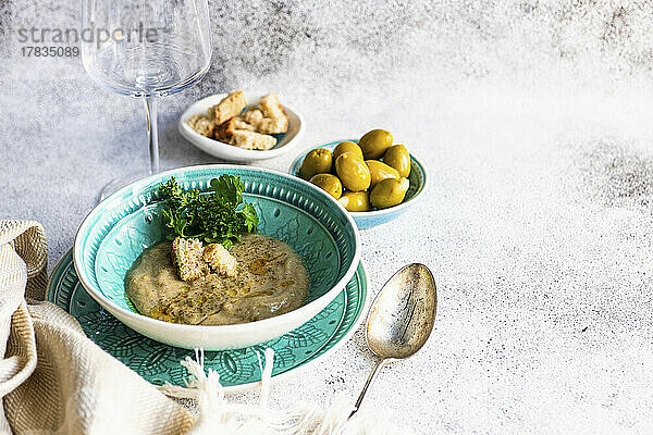 Vegetarische Pilzsuppe serviert dazu grüne Oliven und Croutons
