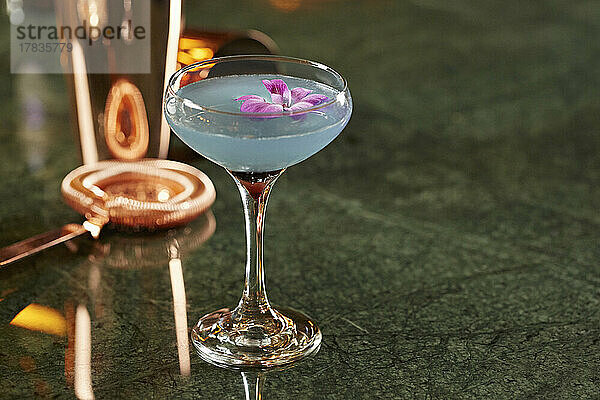 Blue Lagoon Cocktail  garniert mit einer violetten Blume