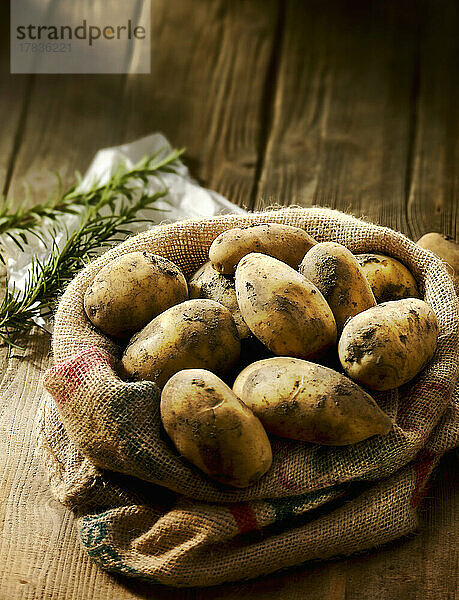 Kartoffeln im Jutesack dahinter Rosmarin