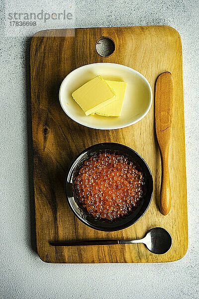 Roter frischer Forellenkaviar in einer Schüssel daneben Schälchen mit Butter