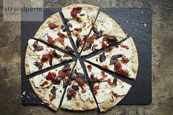 Pizza mit Halloumi  schwarzen Oliven und Paprika  geschnittena auf Schieferplatte