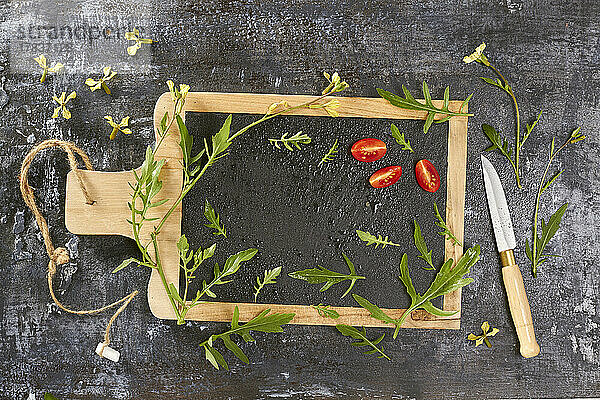 Rucola und Tomaten auf Holzbrett mit Schiefertafel