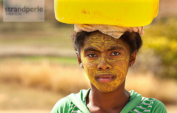 Porträt einer Frau  die Wasser trägt  mit bemaltem Gesicht zum Schutz der Haut vor der Sonne  Isalo  Madagaskar  Afrika
