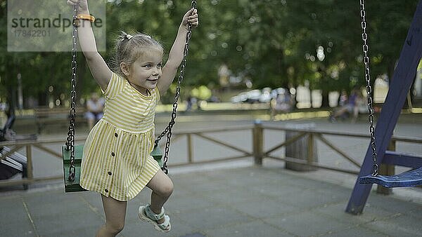 Nettes kleines Mädchen reitet auf einer Schaukel auf dem Spielplatz. Kind Mädchen spielen auf dem Spielplatz im Stadtpark. Odessa  Ukraine  Europa