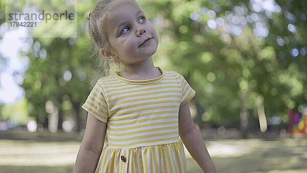 Süßes kleines Mädchen hört Musik und singt mit. Close-up-Porträt von Kind Mädchen steht in einem Stadtpark und hört zu Musik. Odessa  Ukraine  Europa