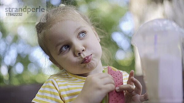 Nahaufnahme von niedlichen kleinen Mädchen isst Eiscreme. Nahaufnahme von Kind Mädchen sitzt auf Parkbank und isst Eis. Odessa  Ukraine  Europa