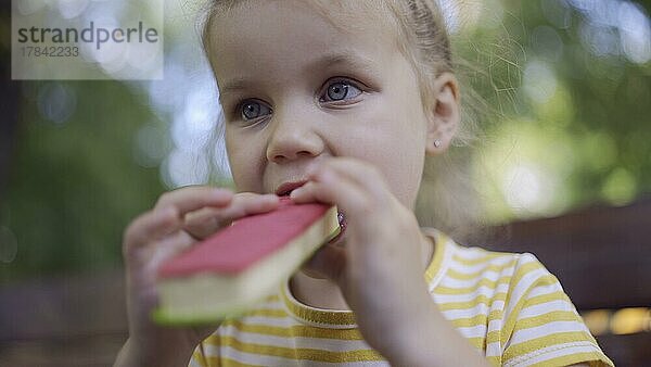 Nahaufnahme von niedlichen kleinen Mädchen isst Eiscreme. Nahaufnahme von Kind Mädchen sitzt auf Parkbank und isst Eis. Odessa  Ukraine  Europa