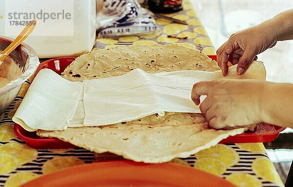 Zubereitung des traditionellen nicaraguanischen Quesillo. Person bei der Herstellung von köstlichem nicaraguanischem Käse. Traditioneller Käse mit eingelegten Zwiebeln  Hände bei der Zubereitung des traditionellen nicaraguanischen Quesillo