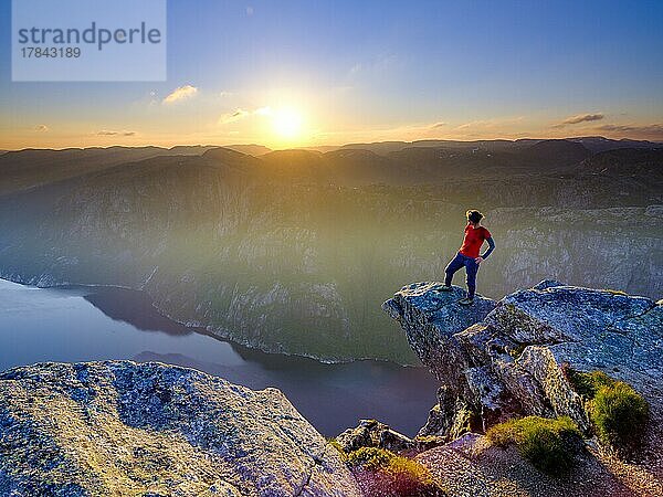 Frau steht auf einer Felsnase am Kjerag über dem Lysefjord  Sonnenuntergang  Lyseboten  Rogaland  Norwegen  Europa