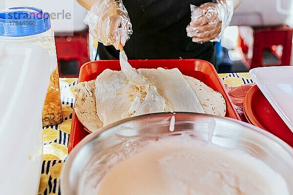 Nicaraguanischer Quesillo  traditionelles mittelamerikanisches Essen quesillo. Hände bei der Herstellung eines nicaraguanischen Quesillo. Nahaufnahme der Hände bei der Herstellung eines traditionellen Quesillo mit eingelegten Zwiebeln