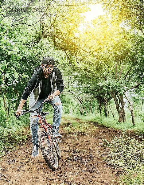 Person auf dem Fahrrad in der Landschaft  Porträt eines Mannes in Kappe auf dem Fahrrad auf einer Landstraße  Fahrradfahrer Person auf seinem Fahrrad auf einer Landstraße Wald. Ein Mann fährt ein Fahrrad auf dem Lande