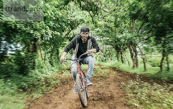 Porträt eines Mannes in Kappe auf dem Fahrrad auf einer Landstraße  Person auf dem Fahrrad in der Landschaft  Radfahrer Person auf seinem Fahrrad auf einer Landstraße Wald. Teenager auf dem Fahrrad auf dem Lande