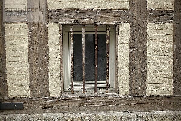 Altes Fenster mit Fenstergitter an einer braunen Hauswand mit Fachwerkbalken  Quedlinburg  Sachsen-Anhalt  Deutschland  Europa