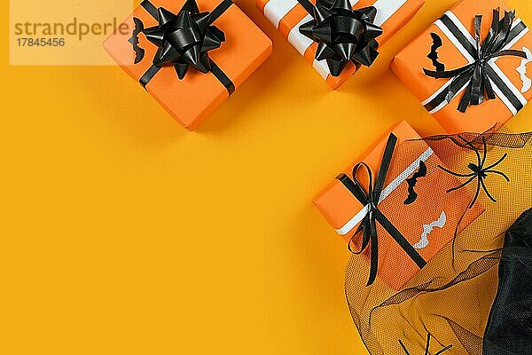 Traditionell dekorierte Geschenkboxen für Halloween mit kleinen Fledermäusen und Netz mit Spinnen auf gelbem Hintergrund mit leerem Kopierraum