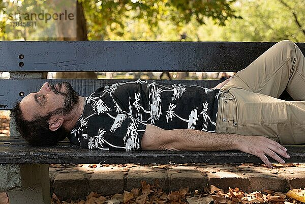 Ein Mann schläft auf einer Bank im Park