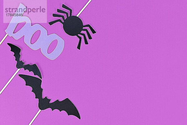 Halloween Hintergrund mit Foto Requisiten auf Stöcken in Form von schwarzen Fledermäusen  Spinne und violett Wort boo auf lila Hintergrund mit Kopie Raum