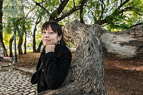 Eine Frau posiert mit Blick in die Kamera in einem öffentlichen Park
