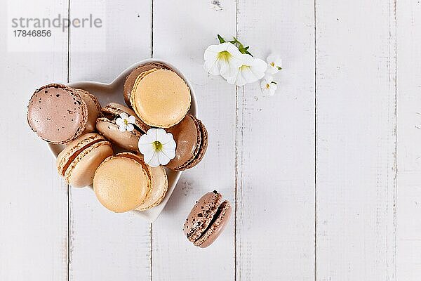 Braune  beige und cremefarbene französische Macarons auf herzförmigem Teller mit Kopierfeld